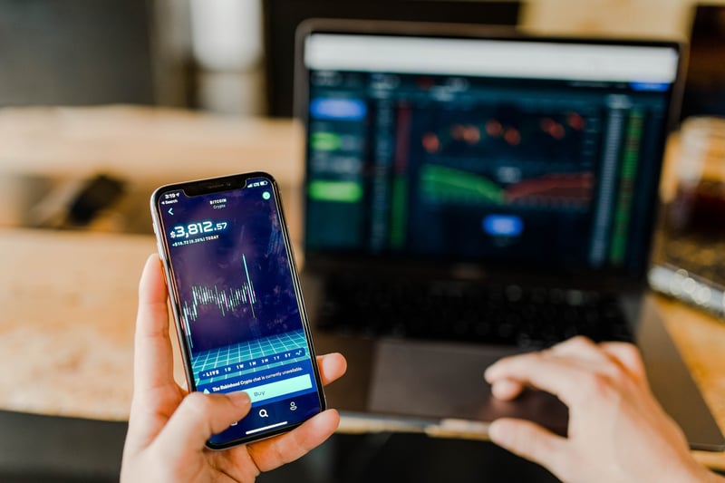 Business person analyzing stocks on phone and laptop