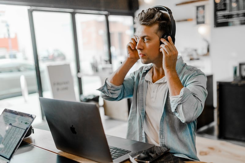 Person putting on headphones while working on laptop